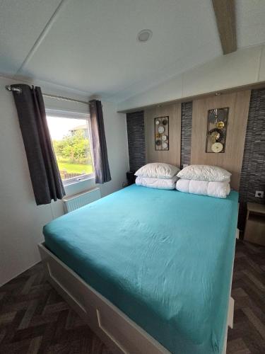 a bedroom with a large blue bed with a window at PRACHTiG CHALET ZONNESTRAAL in Westerland
