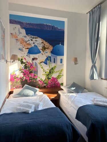 two beds in a room with a painting on the wall at La Melodia in Kościerzyna