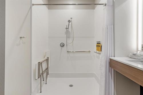 a white bathroom with a shower and a sink at Best Western Plus Marquette Hotel & Suites in Marquette