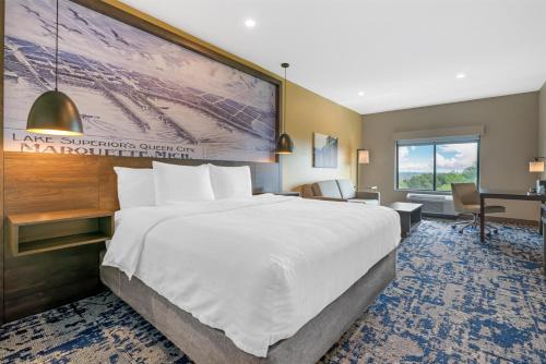 a hotel room with a large bed and a desk at Best Western Plus Marquette Hotel & Suites in Marquette