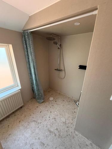 a bathroom with a shower in a room with a window at Villa Barkaboda in Barkaboda