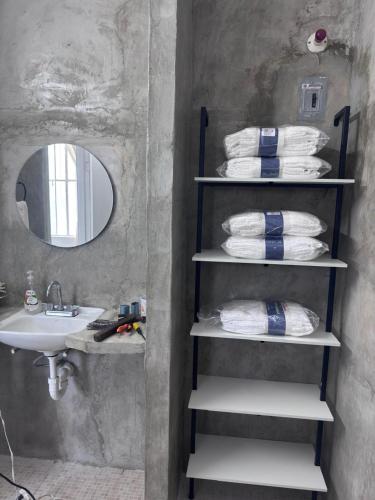 a bathroom with a sink and a shelf with towels at Casa verde El Platanar con Jardín Tropical Calkiní in Calkiní