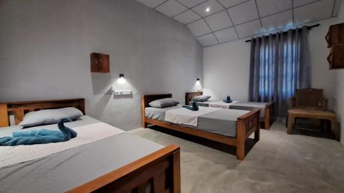 a bedroom with three beds in a room at Holabay Surf Hostel in Arugam Bay