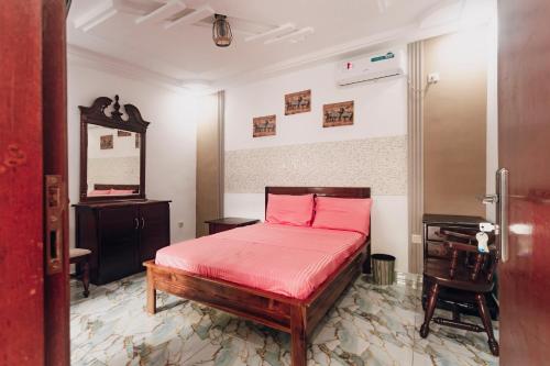 ein Schlafzimmer mit einem Bett mit rosa Bettwäsche und einem Schreibtisch in der Unterkunft La clémentine in Jacqueville