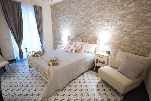 a bedroom with a bed and a chair and a brick wall at Sinfonia Barocca in Modica