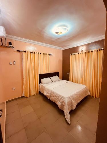 a bedroom with a large bed with yellow curtains at Seyi Homes in Hausa