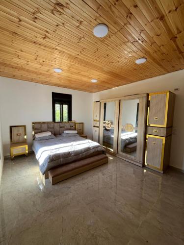 a large bedroom with a bed and a wooden ceiling at زهرة الخليج in Jerash