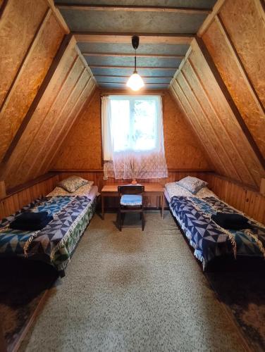 an attic room with two beds and a window at Poilsio nameliai ūkyje Šironija in Ambraziškiai