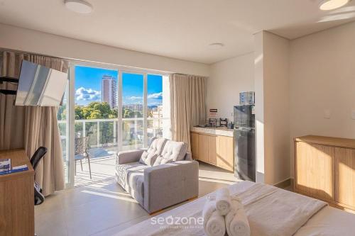 a living room with a couch and a kitchen with a large window at Studio in a cond. w/gym in the city center MSU0301 in Governador Valadares