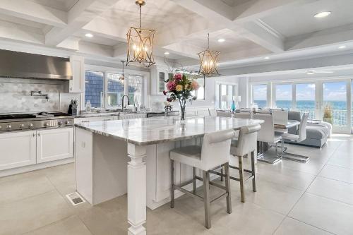 a kitchen with a large white island with a vase of flowers at Sunrise Waterfront Retreat in Milford