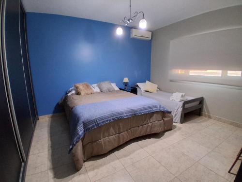 a bedroom with a bed and a blue wall at Dos Lapachos in San Fernando del Valle de Catamarca