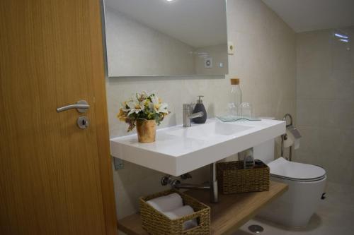 a bathroom with a white sink and a toilet at Alojamento Madeira`s in Videmonte