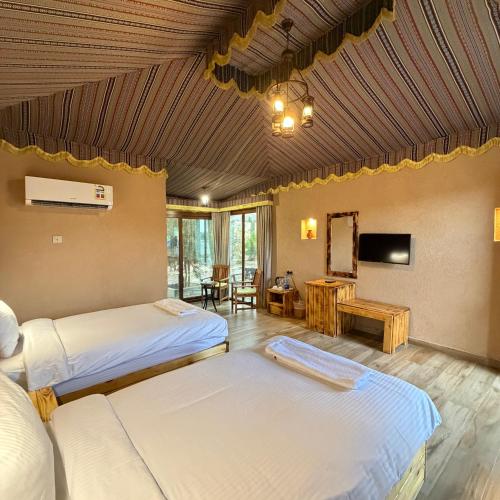 a hotel room with two beds and a television at Jebel Shams Resort منتجع جبل شمس in Dār Sawdāʼ