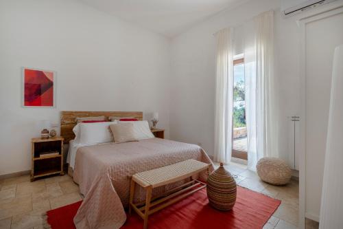 a white bedroom with a bed with a red rug at Oltre i coni in Santa Lucia