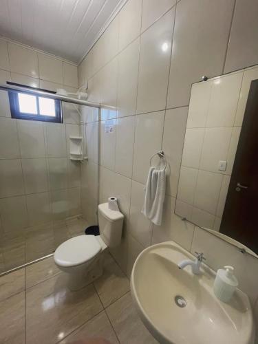 a white bathroom with a toilet and a sink at Pousada Neca Raabe in Pântano Grande