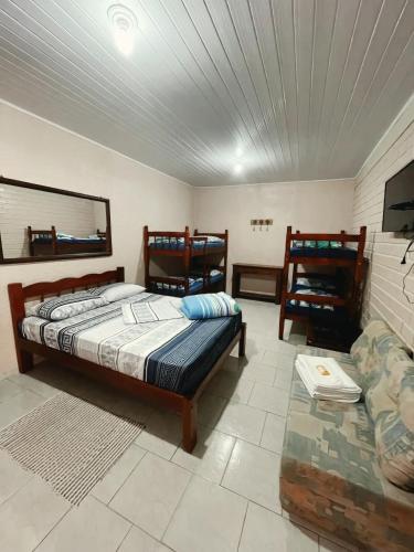 a bedroom with a bed and a couch and a tv at Pousada Neca Raabe in Pântano Grande