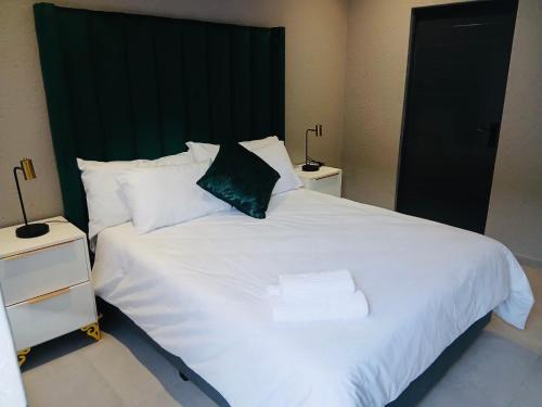 a large white bed with a green headboard and two night stands at Gold Pepper Boutique Guesthouse in Siyabuswa