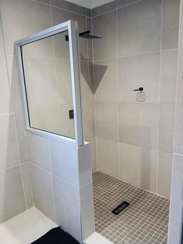 a shower with a glass door in a bathroom at Gold Pepper Boutique Guesthouse in Siyabuswa
