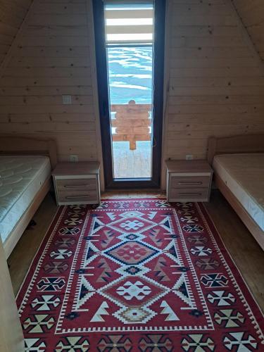 an attic room with a rug and two beds and a window at Suvi Vrh mountain cabin in Gacko