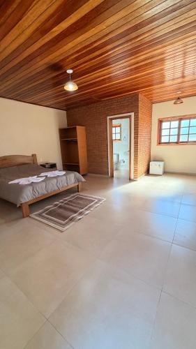 a bedroom with a bed and a wooden ceiling at Chalés Nascer do Sol in Camanducaia