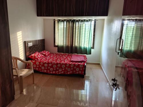 a bedroom with a bed and a chair and windows at SVL HomeStay in Chik Ballāpur