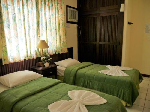 2 Betten in einem Hotelzimmer mit grüner Bettwäsche in der Unterkunft Grimms Pousada de Contos in Porto de Sauipe