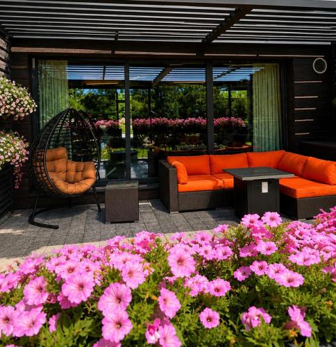 an outdoor patio with pink flowers and an orange couch at Hotel Jakuszyce Sport & Spa in Szklarska Poręba