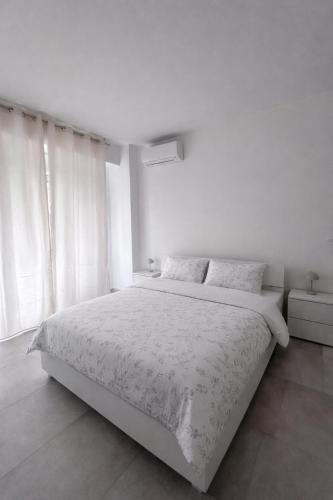a white bedroom with a large bed and a window at Venera Rooms in Caltanissetta