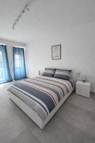 a white bedroom with a large bed with blue curtains at Venera Rooms in Caltanissetta