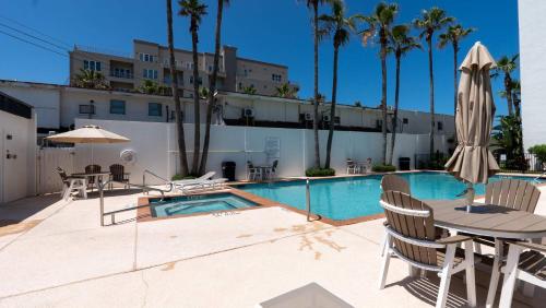 a pool with chairs and a table and a umbrella at Beachfront 2BR 5th Floor Views Wakable SPI in South Padre Island