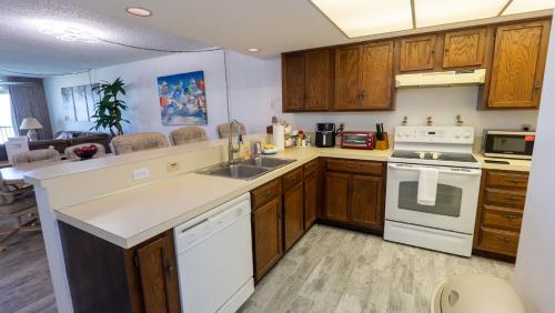 a kitchen with wooden cabinets and white appliances at Beachfront 2BR 5th Floor Views Wakable SPI in South Padre Island