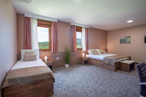 a bedroom with two beds and two windows at B&B Villa Angy in Korenica