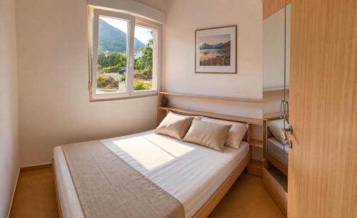 a small bedroom with a bed and a window at PRCPORTOapartmani in Herceg-Novi