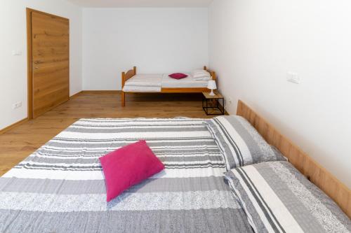 a bedroom with a bed with a pink pillow at Apartma Luketovi in Vojščica