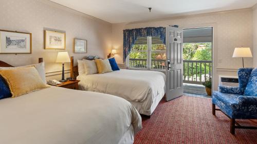 a hotel room with two beds and a chair and a window at Green Mountain Inn in Stowe