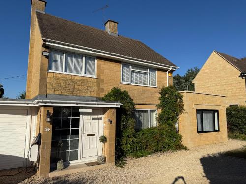 a brown brick house with a white garage at Penderels, Willersey in Broadway