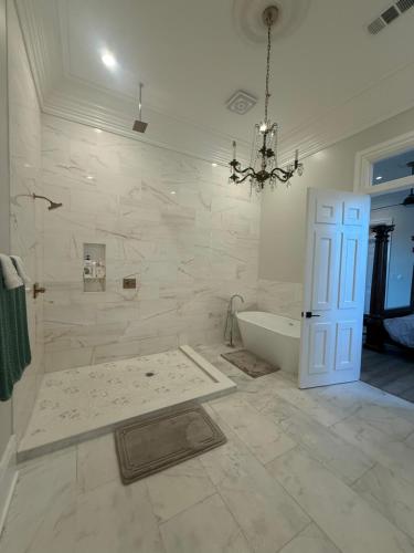 a white bathroom with a tub and a chandelier at Blue Crawfish Boutique Hotel & Pool Bar in New Orleans
