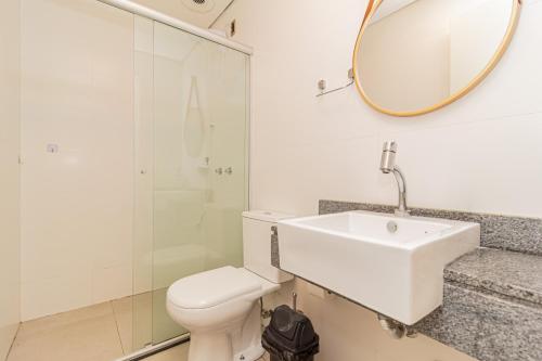 a bathroom with a toilet and a sink and a mirror at Loft Centralíssimo com Garagem in Pelotas