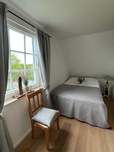 a bedroom with a bed and a chair and a window at Haus-Moewe-Jonathan-Wohnung-1 in Morsum