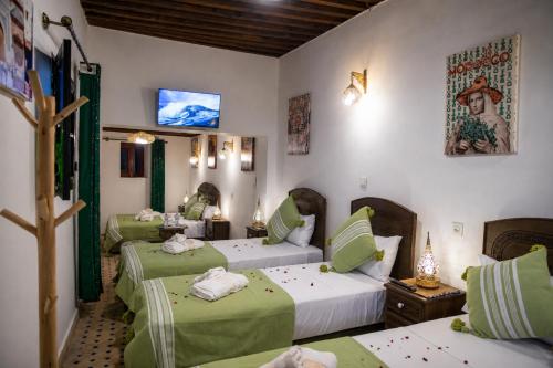 a room with three beds with green sheets at Riad Al Fanouss in Fez