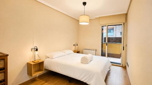 a bedroom with a white bed and a window at Apto Llanes Bajo con terraza - Casa Juanín in Llanes