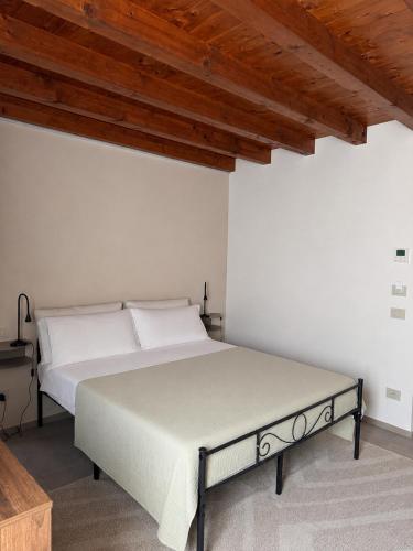 a bed in a white room with a wooden ceiling at B&B Casa Olivia in Gardone Riviera