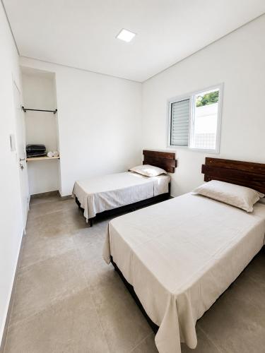two beds in a room with white walls at Mimos Hospedagem in São Paulo