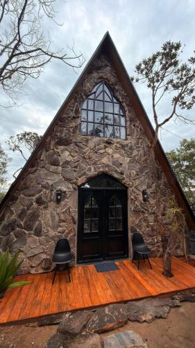 a stone house with two chairs in front of it at O Canto das Fadas Chalés in São Thomé das Letras