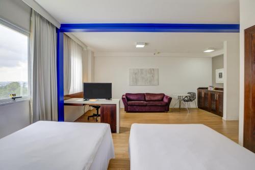 a room with two beds and a desk with a computer at Quality Suites Alphaville in Barueri