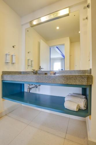 a bathroom with a large mirror and a blue sink at Quality Suites Alphaville in Barueri
