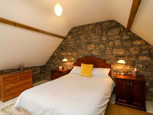 a bedroom with a stone wall with a bed at Childwall Cottage in Tullagher