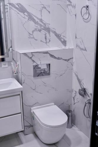 a white bathroom with a toilet and a sink at Lighthouse Hotel in Gyumri