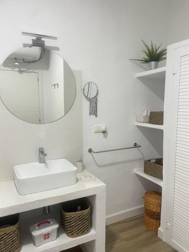 a white bathroom with a sink and a mirror at Patio de Los Barberos in Valle de Abdalagís