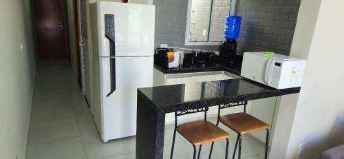 a kitchen with a counter with a refrigerator and stools at Casa 2 Quartos com Ar até 8 Pessoas Jd. Sabiás in Indaiatuba